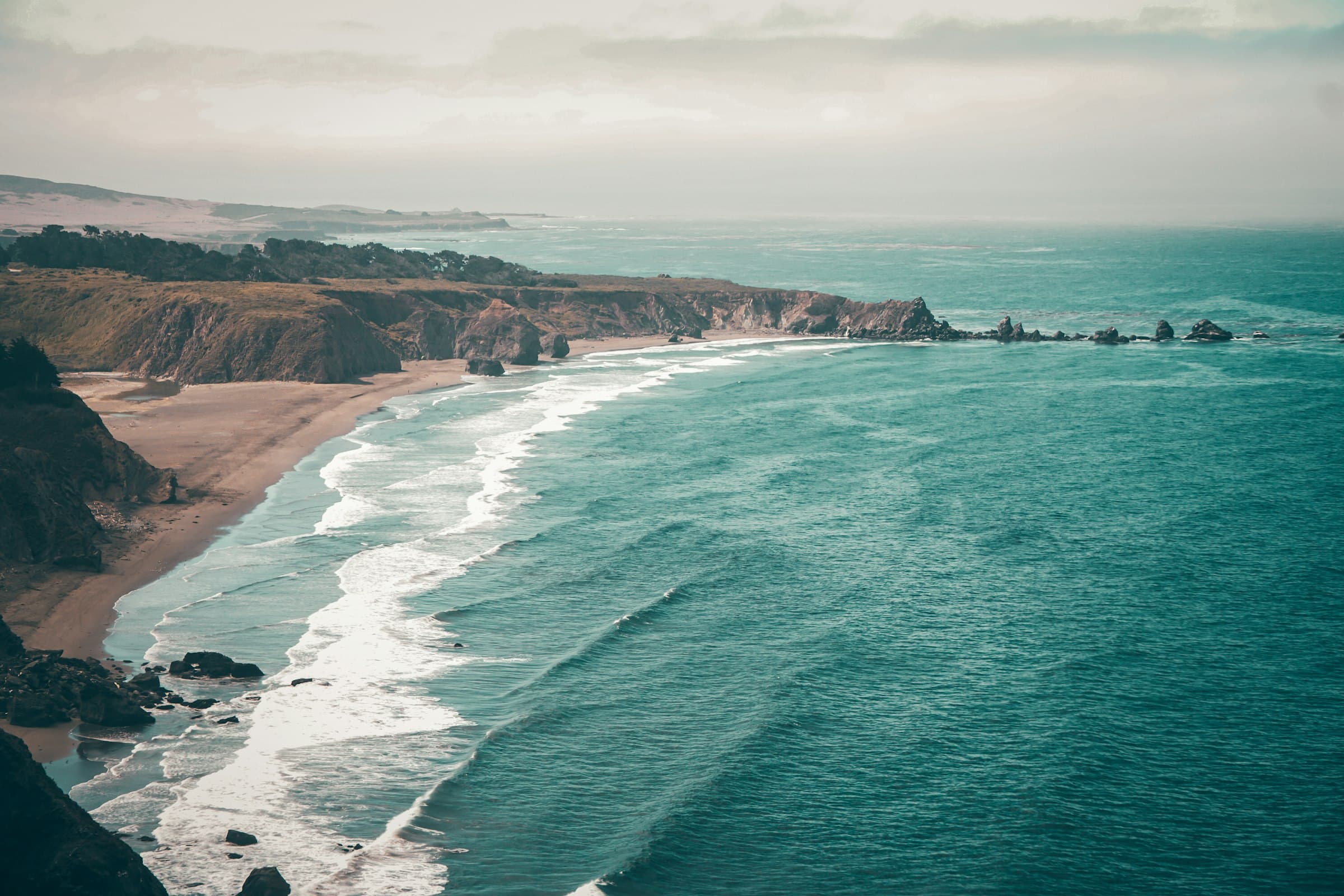 The Pacific coastline from above, surf meeting the bluffs